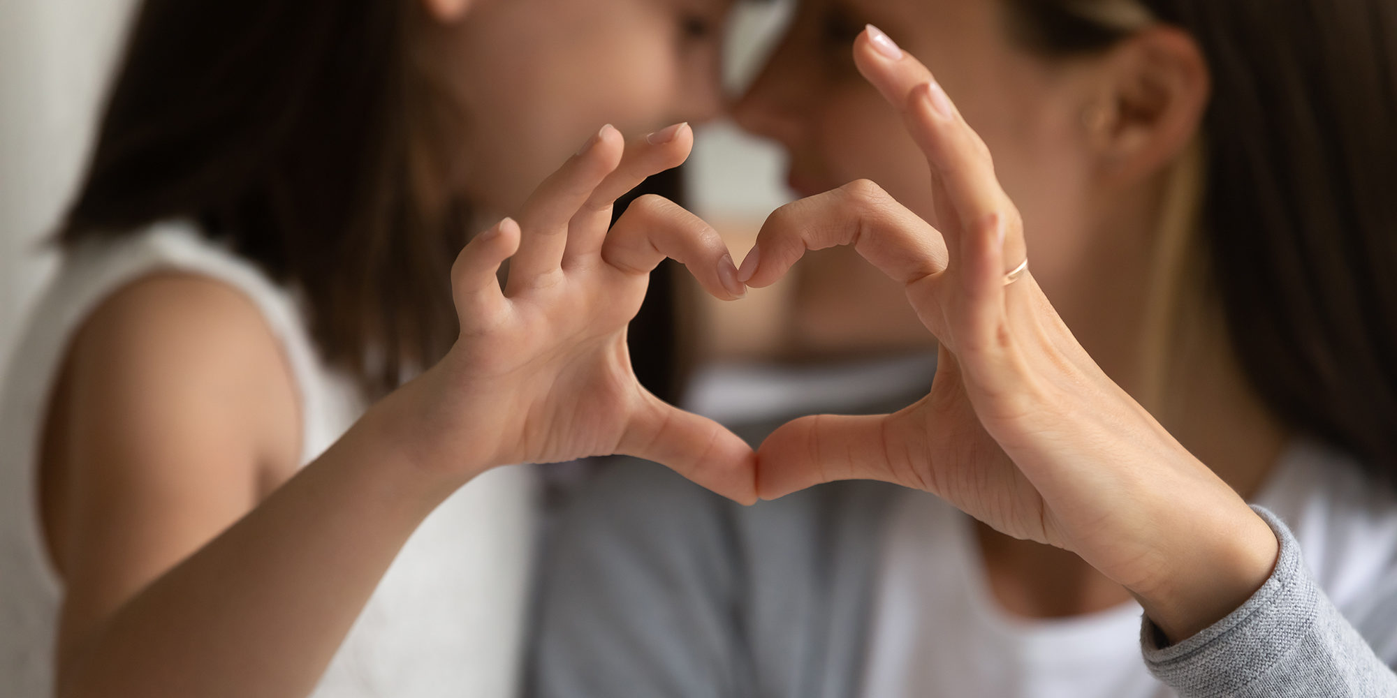 Close up of young mother and cute little daughter make heart sign with hands enjoy close tender moment together, caring mom and grateful small girl child show love and support in family relationships